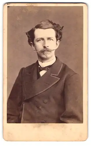 Fotografie W. Schulz-Heim, Carlsruhe, Lange-Str. 217, Portrait junger Mann im Anzug mit Zwirbelbart und Fliege
