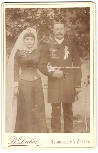 Fotografie B. Dreher, Schopfheim, Portrait Eheleute im schwarzen Hochzeitskleid mit Schleier und Herr im Anzug