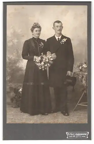 Fotografie G. Gut, Rüti, Portrait Hochzeitspaar im schwarzen Kleid mit Blumenbukett und Herr im Anzug mit Zylinder