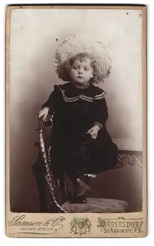 Fotografie Samson & Co., Düsseldorf, Schadowstr. 79, Portrait süsses kleines Mädchen mit Hut im bestickten Kleidchen