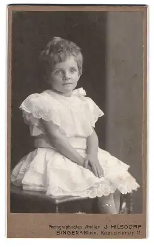 Fotografie J. Hilsdorf, Bingen / Rhein, Kapuzinerstr. 11, Portrait süsses blondes Mädchen im weissen gerüschten Kleidchen