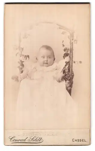 Fotografie Conrad Seldt, Cassel, Portrait süsses Baby im Taufkleidchen