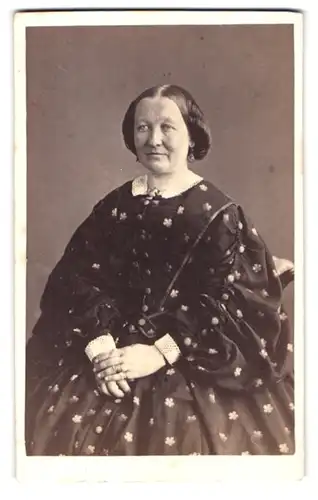 Fotografie Fotograf und Ort unbekannt, Portrait ältere Frau im Blümchenkleid mit zurückgebundenen Haaren