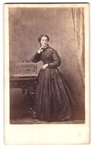 Fotografie Fotograf und Ort unbekannt, Portrait junge Frau im Biedermeierkleid lehnt an einer Schatulle