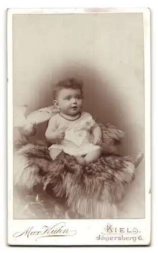 Fotografie Max Kühn, Kiel, Jägersberg 6, Jugendstil, Dame & Ornamente, Rückseitig Baby auf Felldecke sitzend