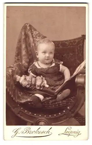 Fotografie Georg Brokesch, Leipzig, Zeitzerstr. 2, Baby mit Puppe auf Sessel sitzend