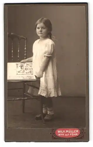 Fotografie Wilhelm Müller, Wyk /Föhr, Sandwall, Mädchen blättert in einem Kinderbuch