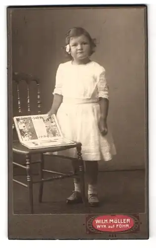 Fotografie Wilhelm Müller, Wyk /Föhr, Sandwall, Mädchen mit Kinderbuch