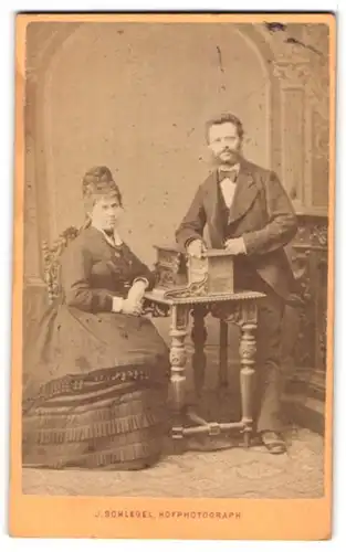 Fotografie J. Schlegel, Reichenberg, Karlsstrasse 34, gestandenes Ehepaar am Sekretär