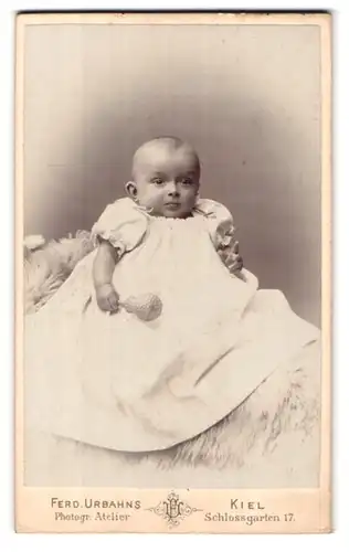 Fotografie Ferd. Urbahns, Kiel, Schlossgarten 17, Baby mit Rassel