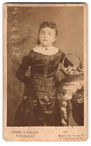 Fotografie Henry J. Sibley, London, 181, Kentisch Town Rd., Portrait elegant gekleidetes Mädchen mit Blumenkorb