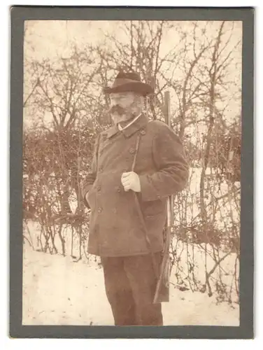 Fotografie Fotograf und Ort unbekannt, Portrait älterer Jäger mit Flinte lauert im Schnee auf Beute, Vollbart