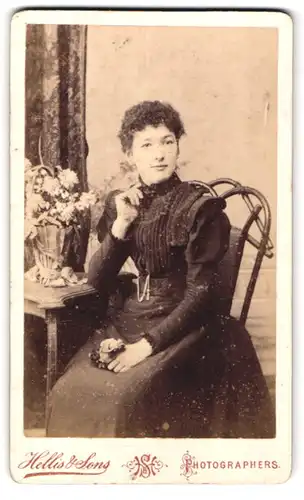 Fotografie Hellis & Sons, London, 211 & 213 Regent Street, sitzende schöne Frau im schwarzen Kleid