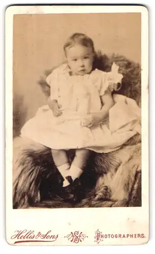 Fotografie Hellis & Sons, London, 211 & 213 Regent Street, kleines Mädchen im weissen Kleid auf Fell sitzend