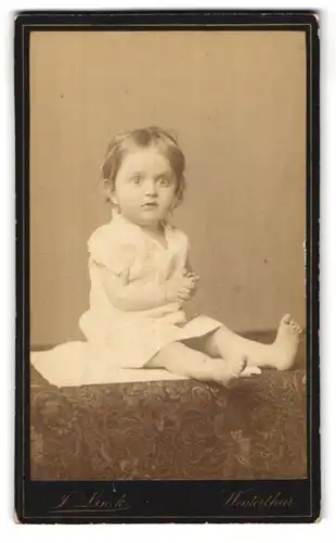 Fotografie J. Linck, Winterthur, Portrait kleines Mädchen im weissen Hemd mit nackigen Füssen