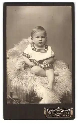 Fotografie A. Meier von Tobel, Zürich, Rennweg 4, Portrait süsses Kleinkind im Kleid mit nackigen Füssen