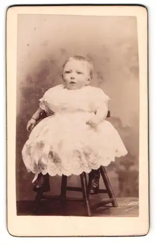 Fotografie A. Louvois, Lez-Bruxelles, Chaussée de Louvain 51, zerknautschtes Kleinkind auf Stuhl hängend
