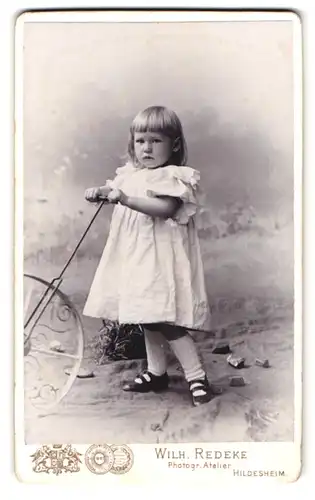 Fotografie Wilh. Redeke, Hildesheim, Kreuzstr. 22, Portrait kleines Mädchen mit Laufrad im weissen Kleid