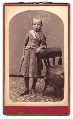 Fotografie Otto Pettersson, Malmö, Stora Torget 8, Portrait Mädchen im grauen Kleid mit Zopf lehnt an einem Stuhl