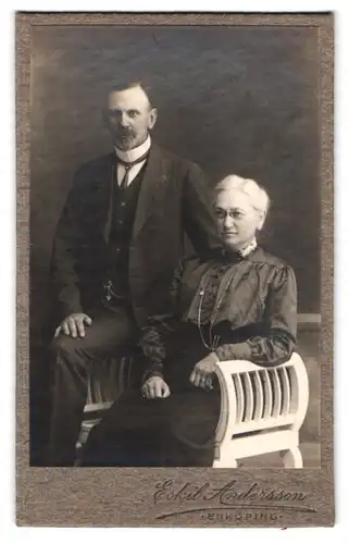 Fotografie Eskil Andersson, Enköping, bürgerlicher Mann und Frau nebeinander auf Bank sitzend