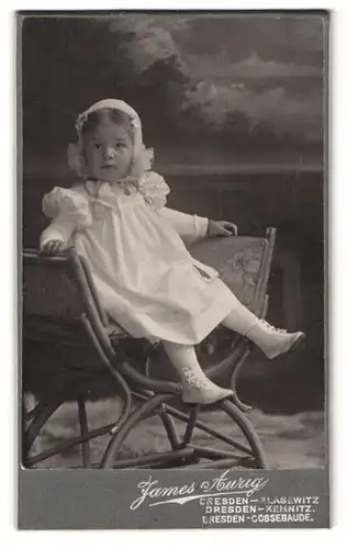 Fotografie James Aurig, Dresden, niedliches kleines Kind mit Haube auf Stuhl sitzend