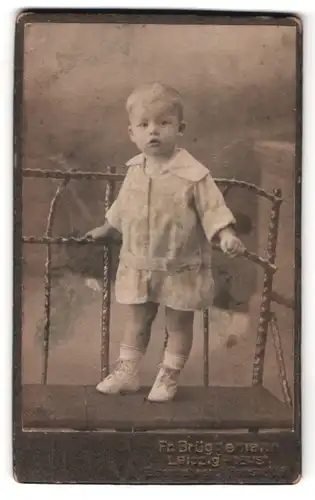 Fotografie Friedrich Brüggemann, Leipzig-Neustadt, Eisenbahnstrasse 1, niedliches Kleinkind an Zaun stehend