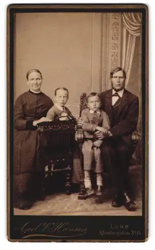 Fotografie Axel V. Hansen, Lund, Klostergatan 14, Portrait Vater und Mutter mit Kindern in Anzügen posieren im Atelier