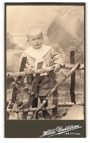 Fotografie Hilda Dahlström, Rättvik, Portrait Kleinkind im Anzug vor einer Studiokulisse
