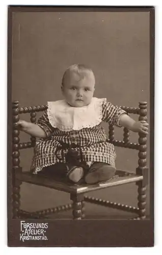 Fotografie Forslunds Atelier, Kristianstad, Portrait Kleinkind im karierten Kleid mit Sabberlatz