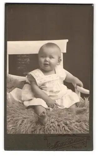 Fotografie Märthar Bohman, Falun, Portrait kleines Kind im weissen Kleid auf einem Fell sitzend