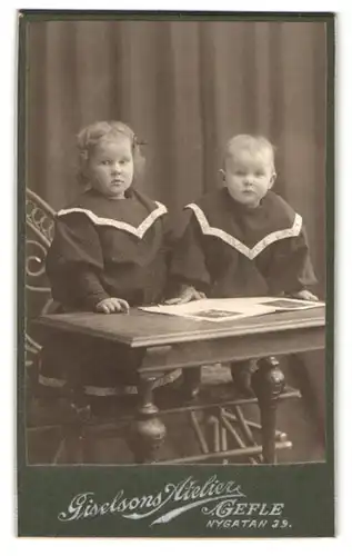 Fotografie Giselsons Atelier, Gefle, Nygatan 39, Portrait zwei Kleinkinder am Tisch stehend mit einem Buch