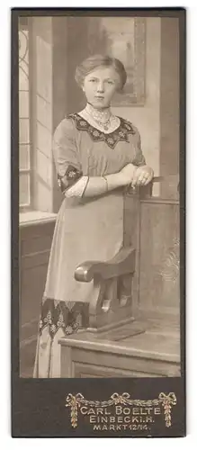 Fotografie Carl Boelte, Einbeck i. H., Markt 12 / 14, Portrait Dame im bestickten Kleid lehnt an eine Holzstuhl