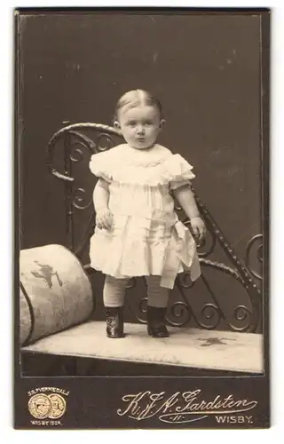 Fotografie K. J. A. Gardsten, Wisby, Skepparegatan 28, Portrait kleines Mädchen im weissen Kleid steht auf einer Bank