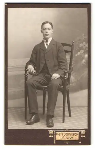 Fotografie H. & H. Johanson, Visby, Södra Kyrkogatan 1, Portrait junger Mann im Anzug sitzt auf einem Stuhl