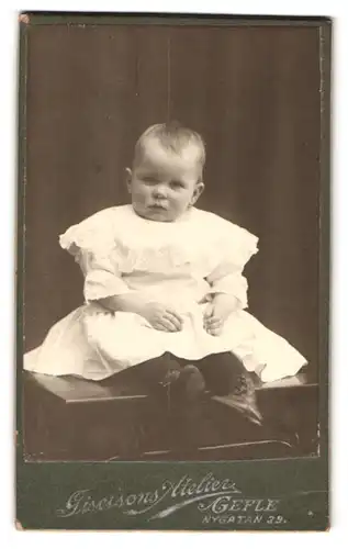 Fotografie Giselsons, Gefle, Nygatan 39, Portrait Kleinkind im weissen Kleid schaut in die Kamera