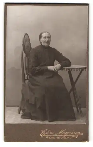 Fotografie Elin Magnison, Askersund, Portrait ältere Dame im Biedermeierkleid sitzt am Tisch