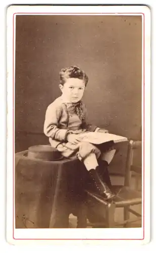 Fotografie Verduron, Nevers, Portrait modisch gekleideter Junge mit einem Buch