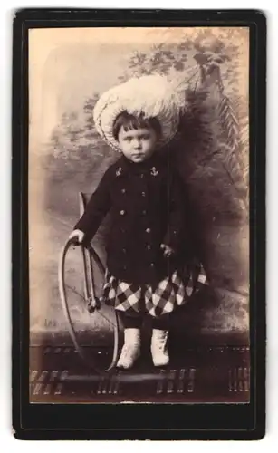 Fotografie Fotograf und Ort unbekannt, Kind im Mantel mit Federhut