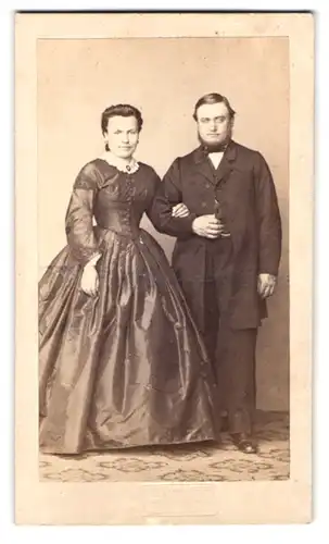 Fotografie Fotograf und Ort unbekannt, Portrait Ehepaar im Biedermeierkleid und Mann im Anzug mit Chin-Strap Bart