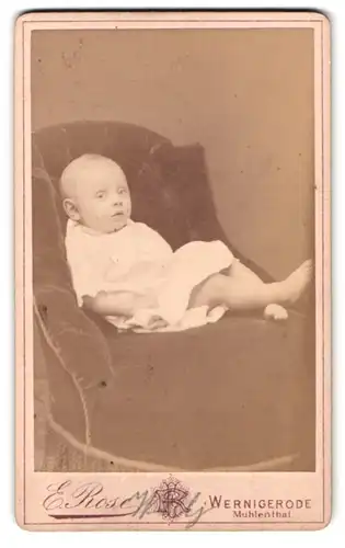 Fotografie E. Rose, Wernigerode, Baby im weissen Taufkleid auf Sessel sitzend