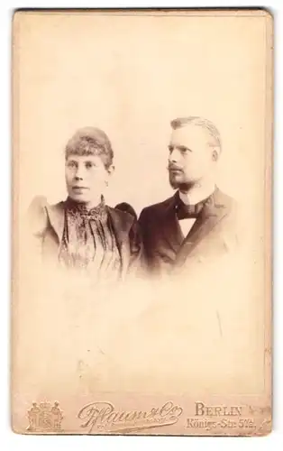 Fotografie Pflaum & Co., Berlin, Königsstr. 57a, Herr im Anzug mit Krawatte nebst Dame im Kleid mit Puffärmeln