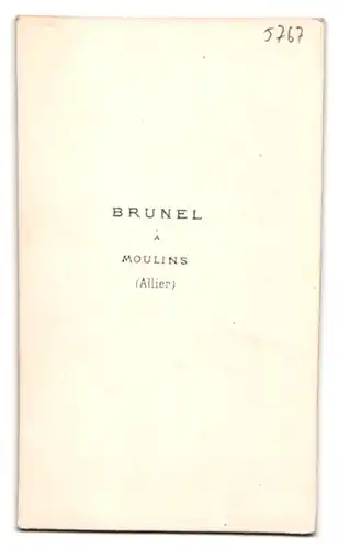 Fotografie Atelier Brunel, Moulins / Allier, Knabe im Anzug mit Fliege an Stuhl lehnend