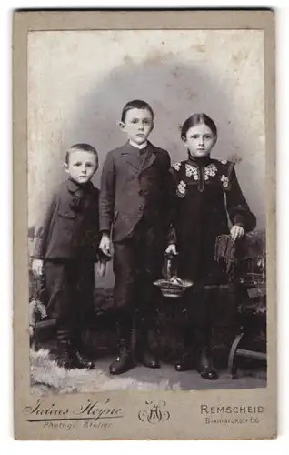 Fotografie Julius Heyne, Remscheid, Bismarckstr. 66, Portrait zwei Brüder mit Ihrer Schwester in Anzügen und Kleid