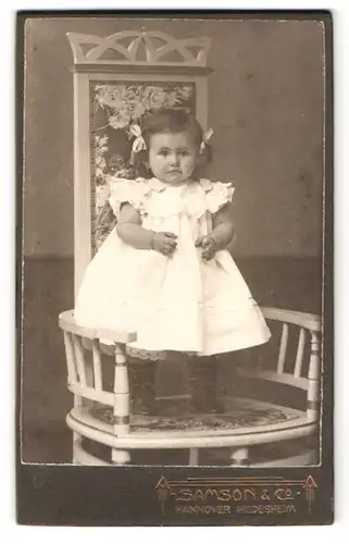 Fotografie Samson & Co., Hannover, Ernst Augustplatz 5, Portrait kleines Mädchen im weissen Kleid mit Zöpfen