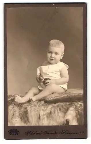 Fotografie Richard Freundt, Hannover, Feldstr. 2a, Portrait Kleinkind mit Bällen auf einem Fell sitzend