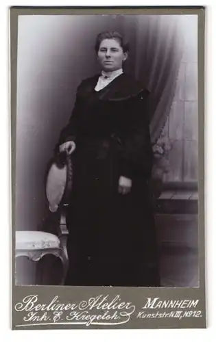 Fotografie Berliner Atelier, Mannheim, Kunststr. N III Nr. 12, Portrait Dame im schwarzen Kleid steht an einem Stuhl