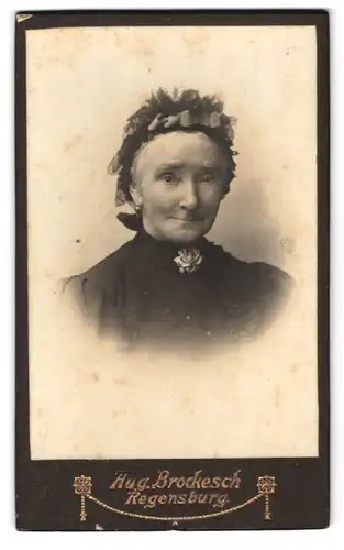 Fotografie Aug. Brockesch, Regensburg, Portrait alte Frau im Kleid mit Kopfbedeckung