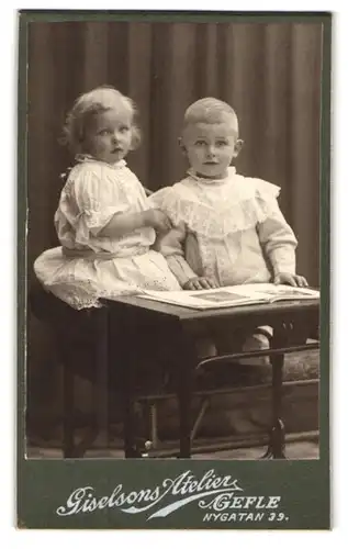 Fotografie Atelier Giselsons, Gefle, Nygatan 39, Hübsches Geschwisterpaar in weissen Kleidern am kleinen Schreibtisch