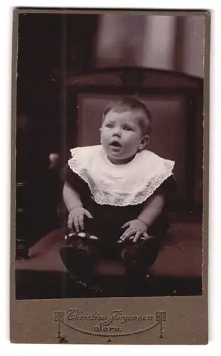 Fotografie Christian Jörgensen, Sorö, Niedlicher Junge mit weissem Lätzchen auf dem Sessel