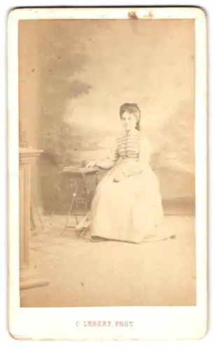 Fotografie C. Lebert, Paris, Rue de Sevres 21, Portrait junge Frau im weissen Kleid sitzend vor einer Studiokulisse